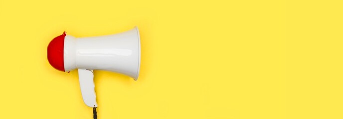Megaphone on yellow background. Panoramic image with with copy space