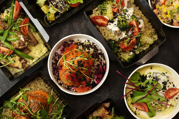 Ready healthy food menu in lunch boxes with fish, meat and vegetable packages as daily courier delivery diet plan isolated on black table background. The concept of ordering takeaway containers.