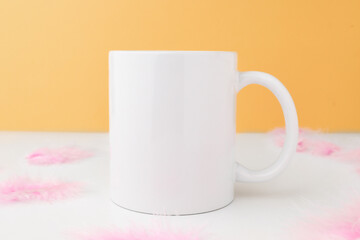 White empty mug for design and logo on an orange background with Easter decor. Mockup with copy space.