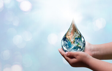 World water day. A globe in the shape of a drop of water falling onto the boy's hand on blue sea background. Elements of this image furnished by NASA . © chathuporn