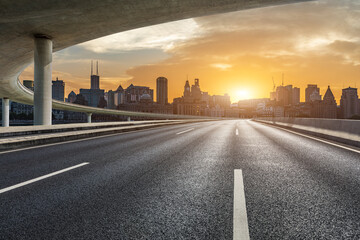 Empty asphalt road and city skyline with modern commercial buildings in Shanghai at sunset, China.