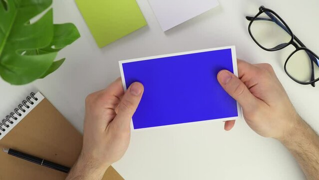 Top view male hands Photo on white background. Blue chroma key image. Place for text or your photos. Desktop in the office. Glasses and notebook top view. Take paper and clean up