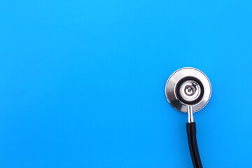Fototapeta na wymiar The stethoscope lies on a blue bright background.