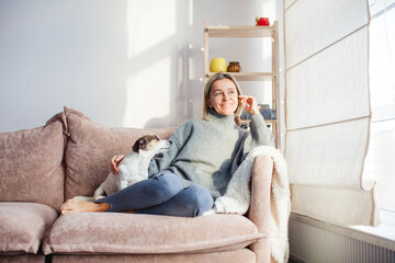 Serene woman housewife lounge sit on sofa with dog  at home