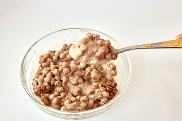 Granola mixed with yogurt in a transparent bowl on a white background. Healthy food.