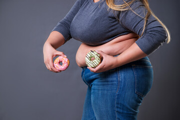 Fat woman posing with donuts on a gray background
