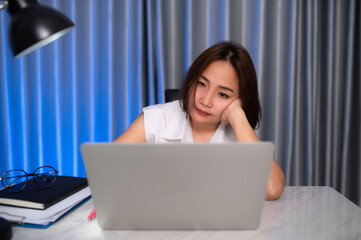 Fototapeta premium Beautiful asian woman working at home on the night,A lot of work from company,bring home work,Work from home concept,Tired from hard work
