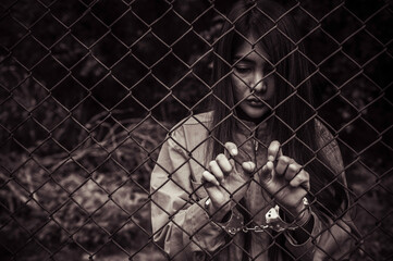 Portrait of women desperate to catch the iron prison,prisoner concept,thailand people,Hope to be free,If the violate the law would be arrested and jailed.