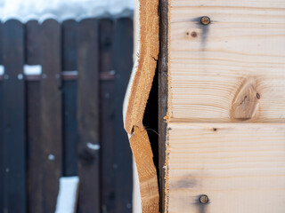 A close-up of a part of a wooden wall made of clapboard of poor quality. A hole in the wall, a...