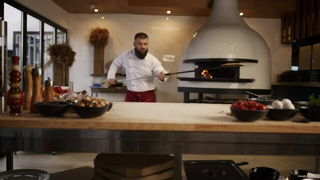 Chef man cooking pizza italian food in professional kitchen restaurant stove.