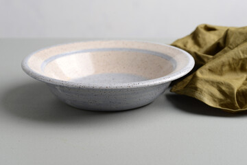 empty bowl with a green linen napkin on a grey table