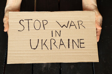 Stop the war in Ukraine written on a sign that a woman holds in her hands from her house in the...