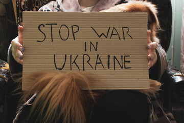 Stop the war in Ukraine written on a sign that a woman holds in her hands from her house in the...