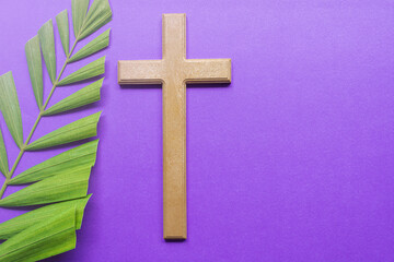 Cross and palm leaves on purple background. Lent season concept.