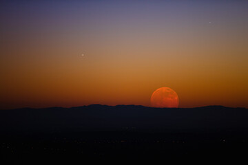 Full Moon rising above distant horizon.