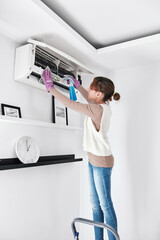 Child girl cleaning aircon filters indoor unit at home.