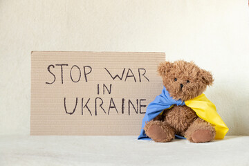 Stop the war in Ukraine is written on a sign that stands at home in Ukraine near a teddy bear....