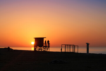 A lifeguard tower silhouette on the golden sunset beach