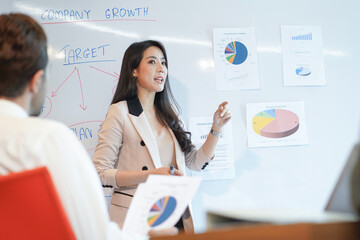 Woman business coach speaker give presentation speaker presenter consulting reporting presenting to CEO or group leader explain graph strategy profit growth result in company meeting  - obrazy, fototapety, plakaty