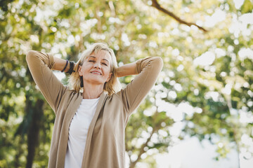 Portrait of happy elderly senior Caucasian woman do stretching and relaxing feel refresh and freedom breathing fresh air with sunlight enjoying a day in the outdoors park on summer - obrazy, fototapety, plakaty