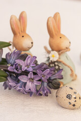 Fototapeta na wymiar Blue hyacinth flowers, egg and ceramic rabbits. Floral Easter background.