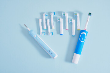 electric toothbrush and multi-colored replaceable nozzles on blue background