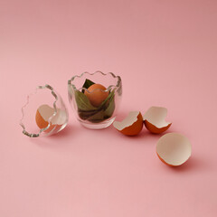 Easter composition, egg in a glass bowl with eggshells like flowers on pink background