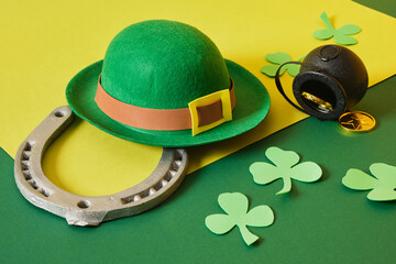 horseshoe, leprechaun hat, coins, cauldron and foamiran clover leaves on green background, st....