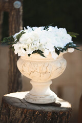 Flowers in a stone vase at a wedding ceremony.