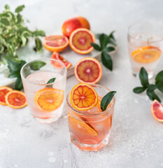 Tonic nonalcoholic mocktail with red Sicilian oranges and ice, grey background. Cold refreshing summer mojito lemonade.