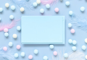 Blank card between pastel pom-poms and feathers on light blue top view
