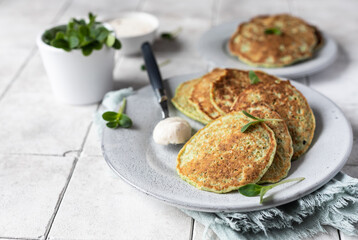 Vegetable fritters served with fresh herbs and dip, tiled background. Vegetarian broccoli or spinach pancakes