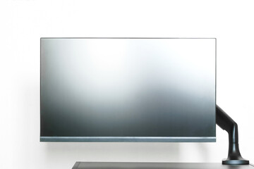 Modern matte computer monitor or TV set is mounted on a small table with a metal bracket....