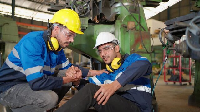 Man labor worker had accident and sit beside cutting equipment at the production line of CNC machine factory. Engineer man help and support him on injured. Safety in industrial factory. Injury at work