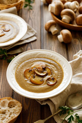 Creamy mushroom soup in a bowl on a wooden table. Traditional soup