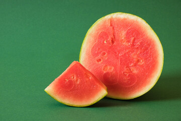 small ripe watermelon cut in half on a green background, small size watermelon variety