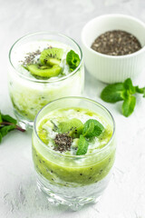 Healthy breakfast chia pudding with kiwi in glass jars on a white table. Clean eating, dieting, vegan food concept. vertical image