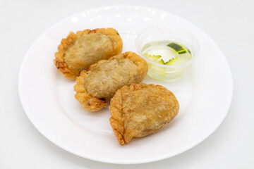 Thai Curry Puffs on a White Plate with Sauce