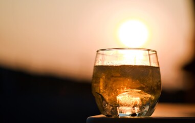 whiskey glass dark background with sunset at dusk