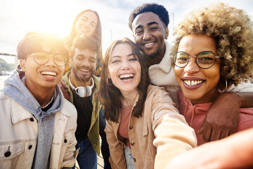 United group of happy young friends having fun while taking a selfie with mobile phone outdoors - Diverse group of millennial people laughing together during vacation - Friendship and holidays concept