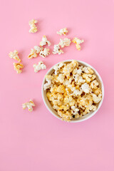 Spilled popcorn on pink background. Movie night concept. Copy space for text