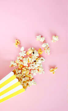 Spilled popcorn on pink background. Movie night concept. Copy space for text