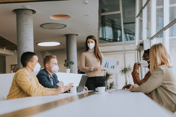 Group of multiethnic business people working together with facial protective masks and preparing new project on a meeting in office