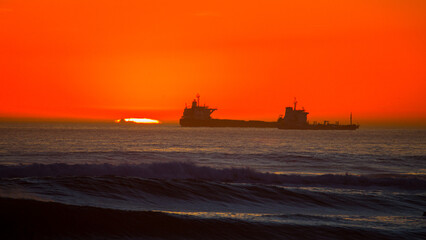 big ship in a huge orange sunset at Praia de Carcavelos