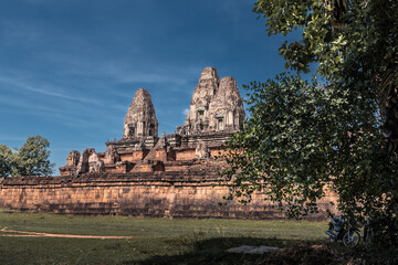 Fototapeta na wymiar Ruins of ancient Cambodian temple among trees in Angkor complex, Siem Reap, Cambodia