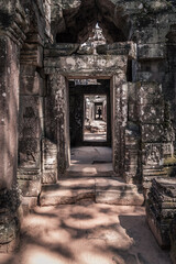 Entrance into long corridor of ancient temple with stone carvings in Angkor Wat, Siem Reap, Cambodia