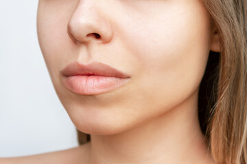 Cropped shot of young caucasian blonde woman's face with perfect lips after lip enhancement. Injection of filler in lips. Result of a lip augmentation. The lower part of the female face