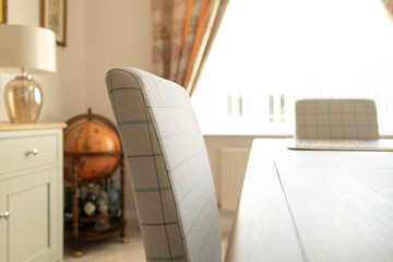 Shallow focus of a home-made fabric dining room chair seen in a bright and inviting show home dining room.