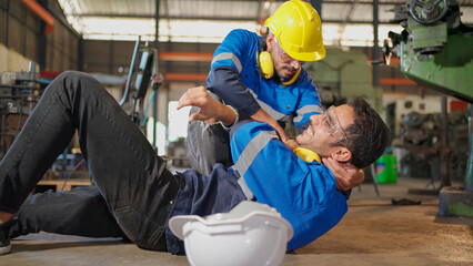 Man labor worker had accident on the floor at the production line of CNC machine factory. Engineer man walk to that area and support him on injured. Safety in industrial factory. Injury at work..