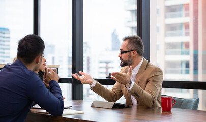 Caucasian male manager explaining work project to colleagues in a meeting room at the office. group of business financial discussing project and working together